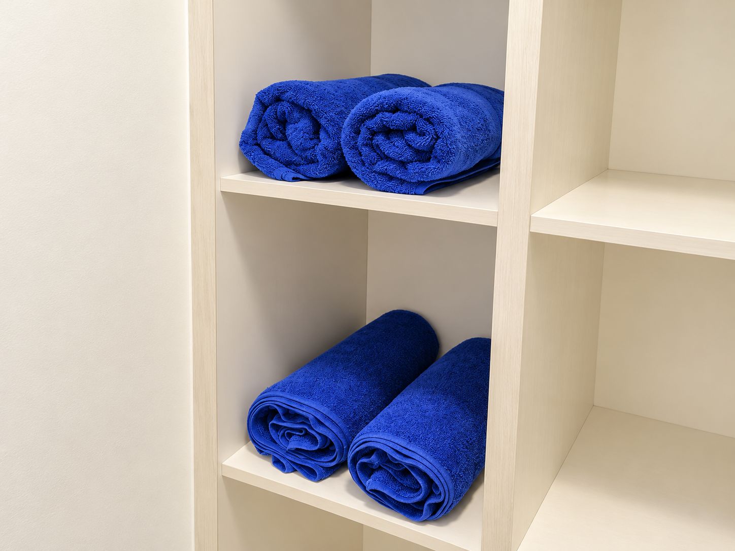 A shelf with three rolled blue towels.