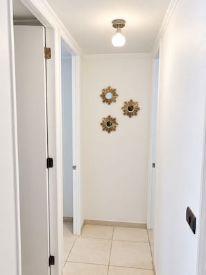 A hallway with white walls, a ceiling light, and three wall-mounted decorative items. - Acogedor Depto a una Cuadra del Mar (Coquimbo)