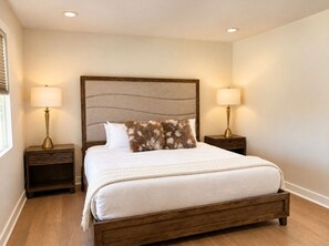A neatly made bed with a wooden frame and a headboard with a textured design.