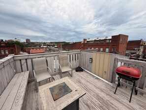Une terrasse sur le toit avec une table en métal, un barbecue et une vue sur le paysage urbain.