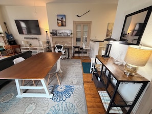 Un salon moderne avec une table à manger en bois, un canapé et un téléviseur fixé au mur.