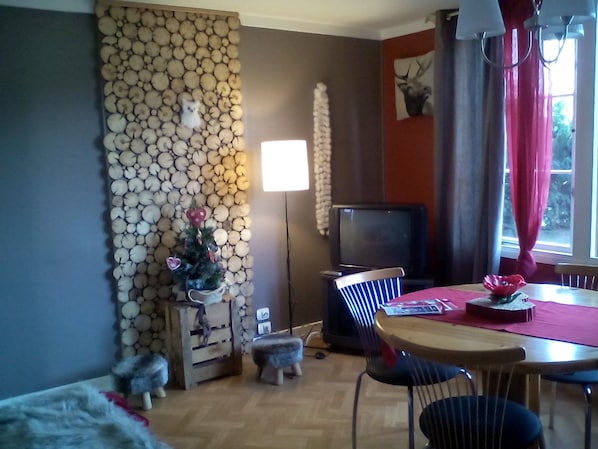 A cozy living room with a fireplace, a television, and a dining area with a table and chairs.