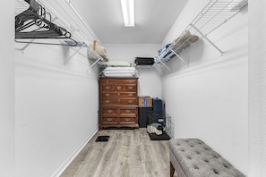 Un pasillo estrecho con un aparador de madera, un banco y estanterías a ambos lados.