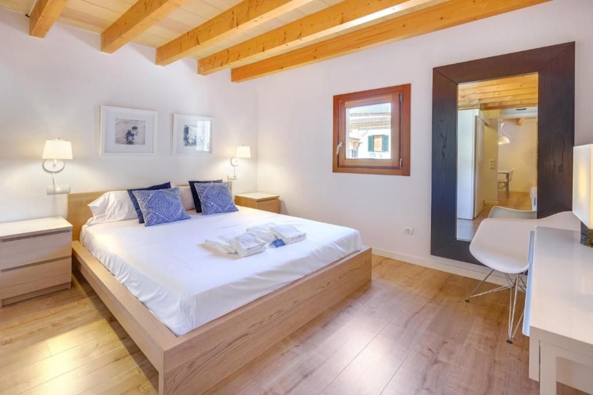 A bedroom with a wooden bed, bedside tables, and wall-mounted lamps.