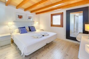 A bedroom with a wooden ceiling, a bed with white bedding, two bedside lamps, and a large mirror. - Urban Suites Palma (Palma)