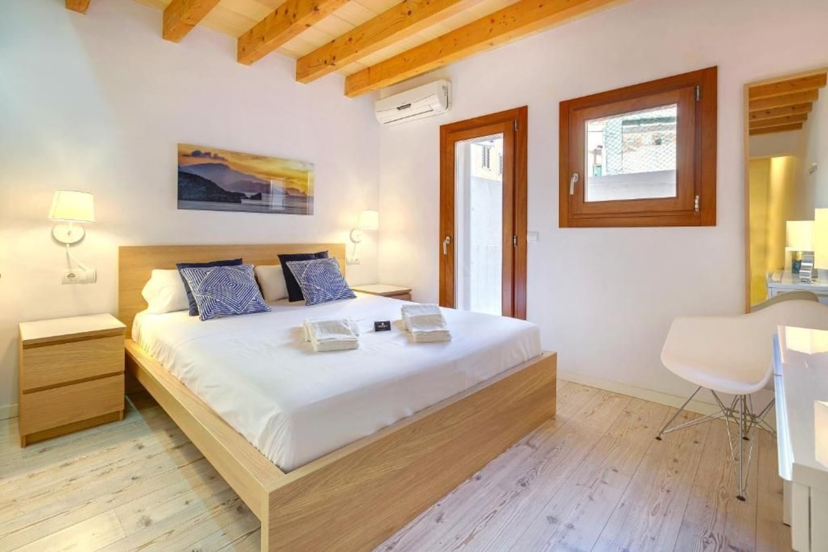 A bedroom with a wooden bed, bedside tables, a desk, and a chair.