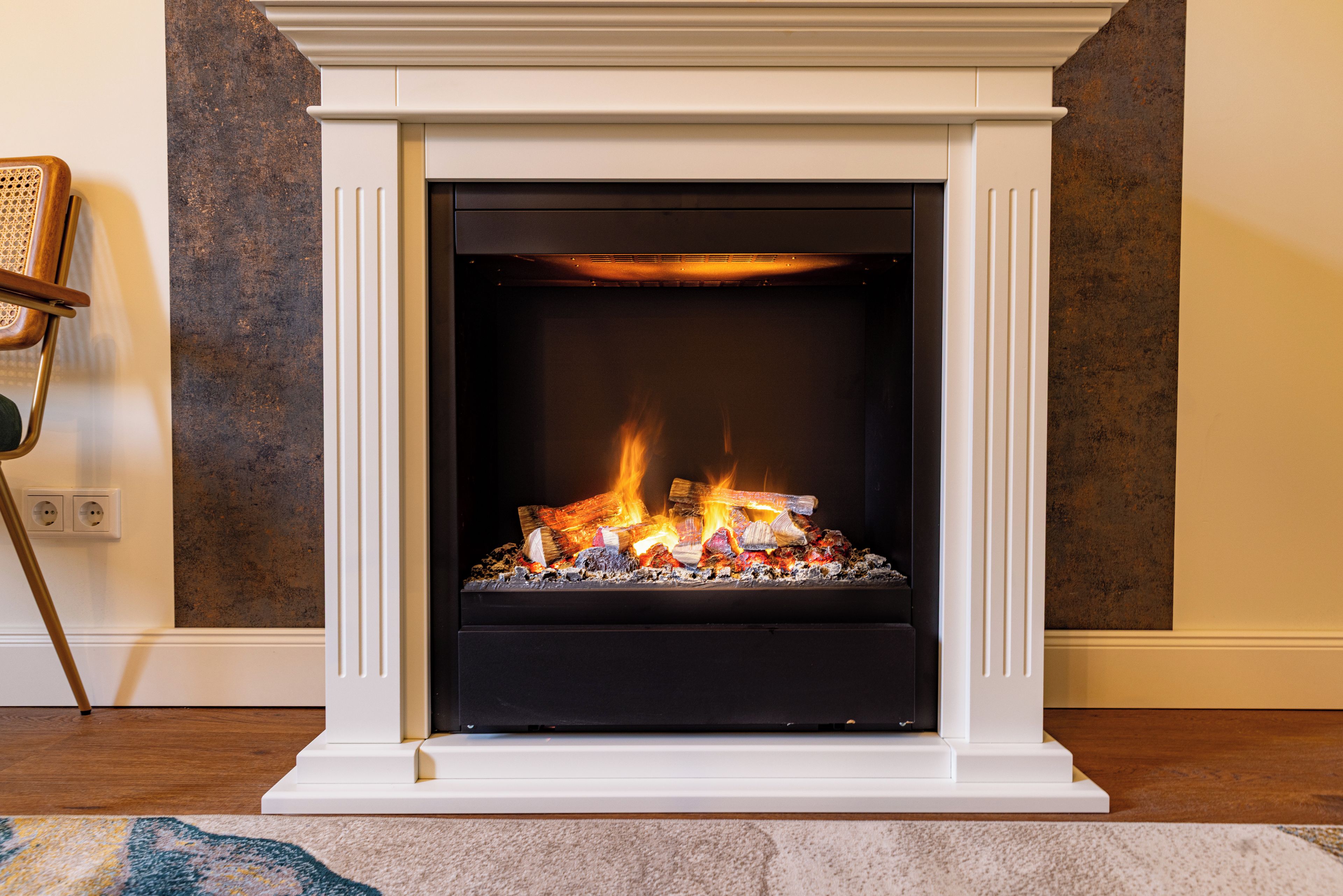 A fireplace with a white mantel and a black surround, burning logs.