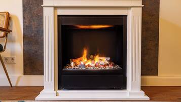 A fireplace with a white mantel and a black surround, burning logs.