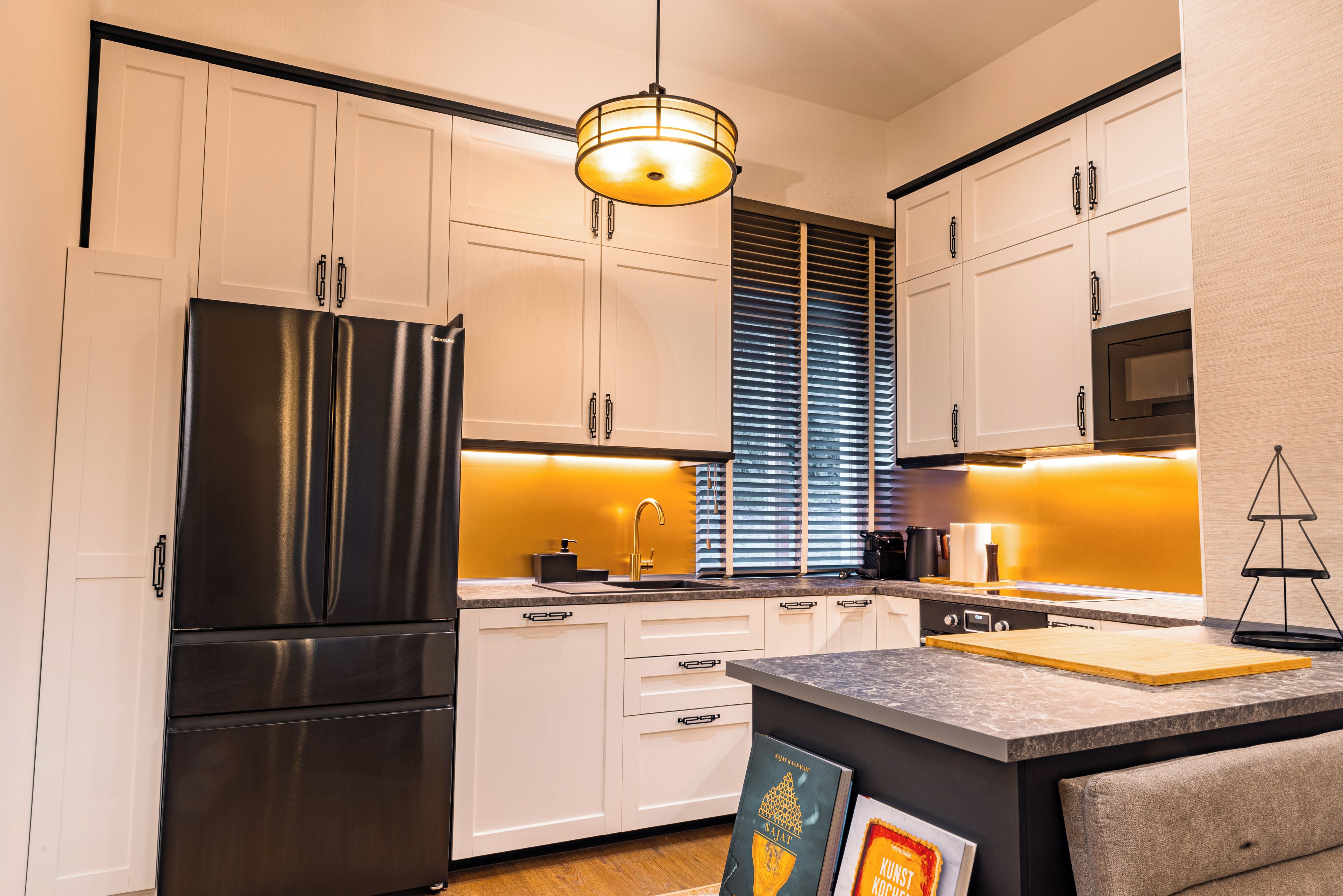 A modern kitchen with white cabinetry, a black refrigerator, and a central island.