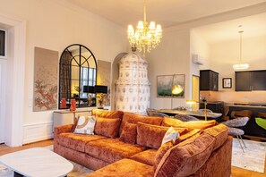 Una sala de estar moderna con un sofá grande, una mesa de comedor y una cocina con armarios y un lavamanos.