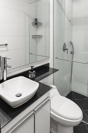 Ein modernes Badezimmer mit einem weißen Waschbecken, einer Toilette und einer gläsernen Duschkabine.