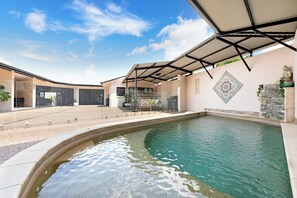 Ein Schwimmbecken mit überdachter Terrasse, einer Buddha-Statue und einer Zierwand.