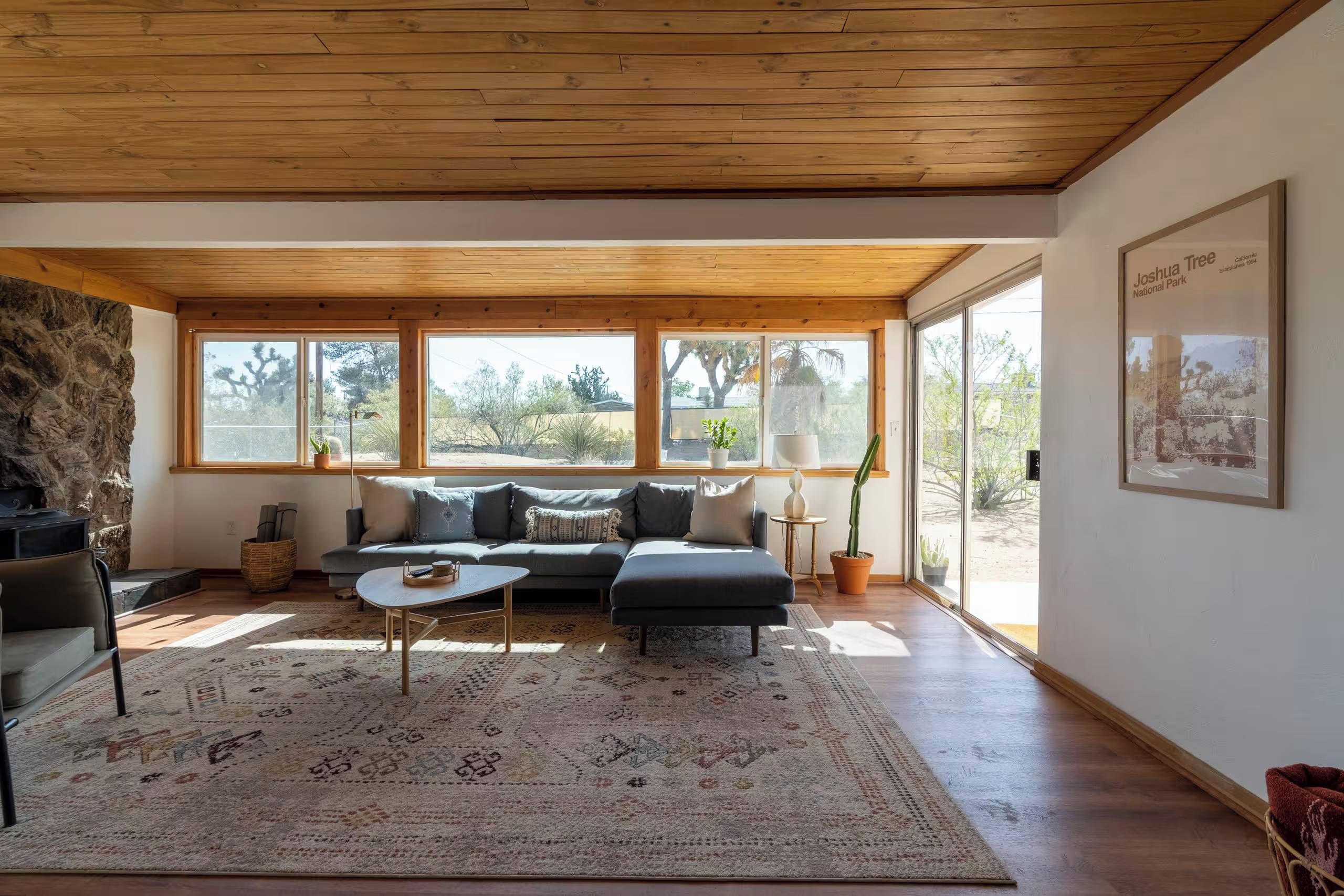 A spacious living room with a large sectional sofa, a coffee table, and a stone wall.