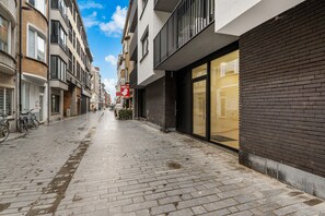 Eine schmale Stadtstraße mit Backsteingebäuden, einem sichtbaren Schaufenster mit einem Schild und einem Fahrrad, das am Gehweg abgestellt ist.