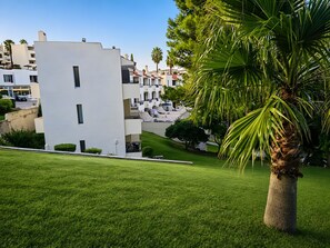 A modern building with balconies, surrounded by well-maintained grass and palm trees. - Apartment 'White Studio - Garden & Sea View' with balcony, Wi-Fi and air conditioning (Albufeira)