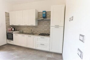 A kitchen with white cabinets, a gas stove, a sink, and a blue box on the countertop. - Vacation home 5 minutes from the Sentiero degli Dei, ideal for Amalfi and the Amalfi Coast (Pianillo)