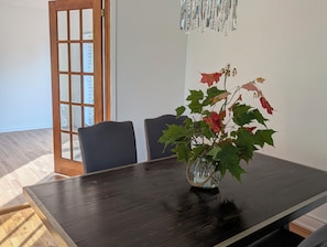 A dining area with a dark wooden table, two chairs, and a vase with green and red leaves. - The Quinte House - Group Friendly with Pool Table (Quinte West)