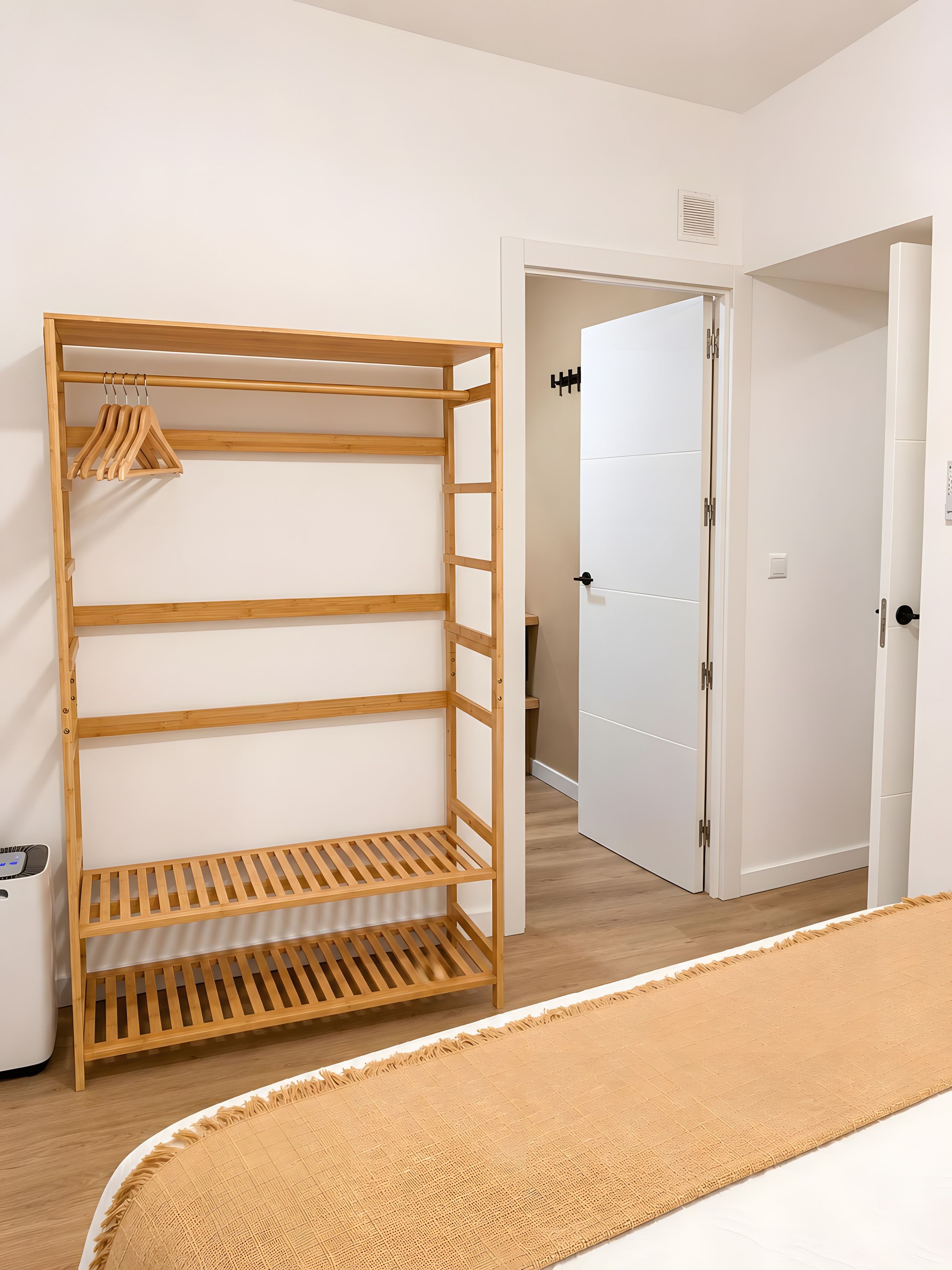 Ein Zimmer mit einem Holfschrank, einem Bett mit beiger Decke und einer weißen Tür.