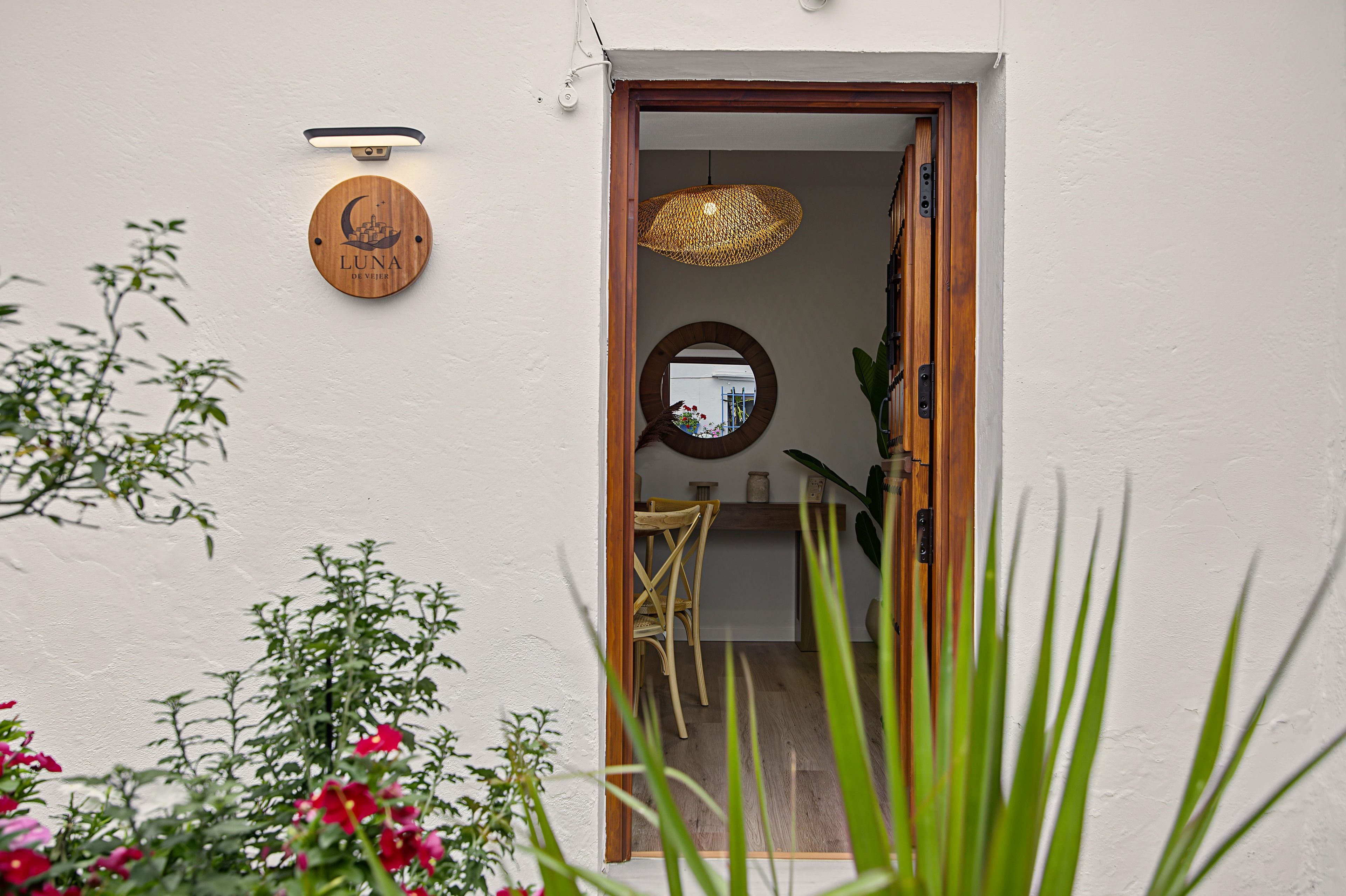 Une porte avec une enseigne en bois, un luminaire suspendu et un miroir au mur.