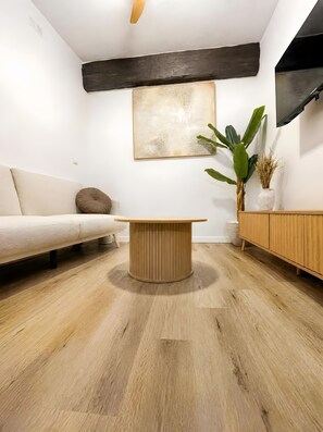 Un salon moderne avec une table basse en bois, un canapé, un grand tableau abstrait, une plante en pot et un meuble en bois.