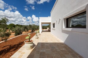 A modern building with a covered outdoor area, potted plants, and a clear sky. - Casa tra gli Ulivi by Perle di Puglia (Ostuni)