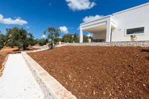 Une maison moderne dotée d’un mur de soutènement en pierre et d’un jardin aménagé.