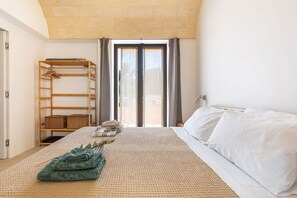 A bedroom with a bed, a wooden shelf, and a window with curtains. - Casa tra gli Ulivi by Perle di Puglia (Ostuni)
