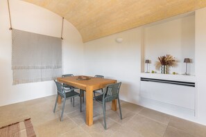 Un coin repas comprenant une table en bois et quatre chaises, une tapisserie murale et un luminaire fixé au mur.