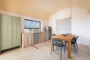 A compact kitchen with a window, a dining area with a table and chairs, and a green cabinet. - Casa tra gli Ulivi by Perle di Puglia (Ostuni)