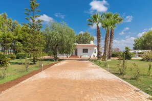 A paved pathway leading to a building with a tiled roof, surrounded by trees and a clear sky. - Villa Carolyta by BarbarHouse (Francavilla Fontana)
