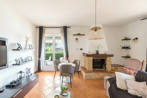 A living room with a fireplace, a dining area, and a TV. - Villa Carolyta by BarbarHouse (Francavilla Fontana)