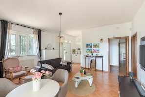 En moderne stue med sofa, sofabord og fjernsyn.