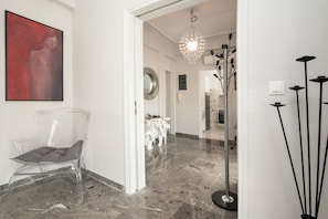 Ein modernes Interieur mit einem klaren Stuhl, einer Pendelleuchte und einer Stehlampe.