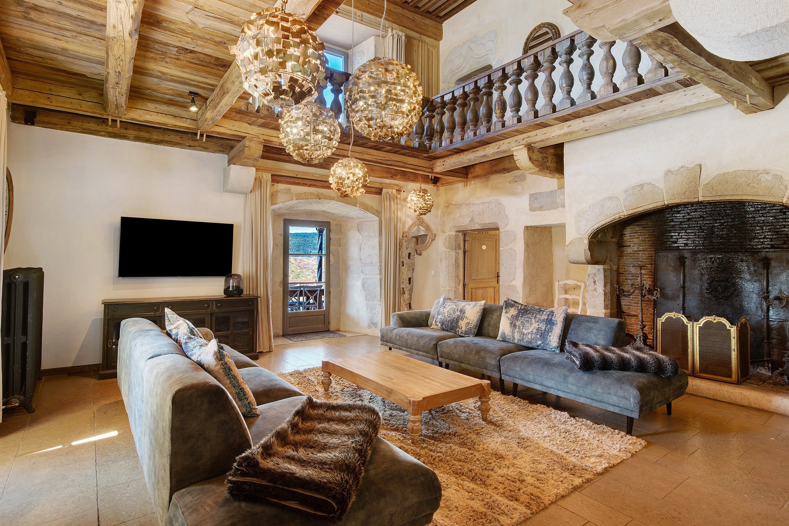 A spacious living room with a fireplace, a television, and a staircase leading to an upper level.