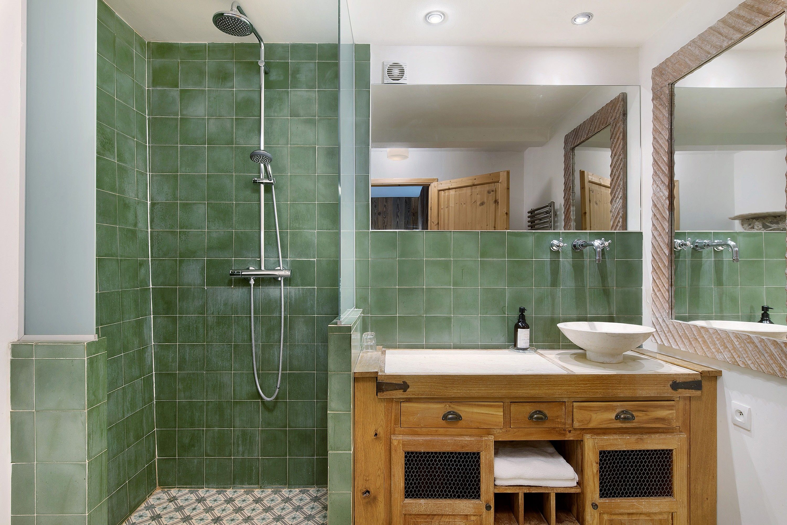 Une salle de bain avec une douche, un lavabo et un meuble-lavabo en bois.