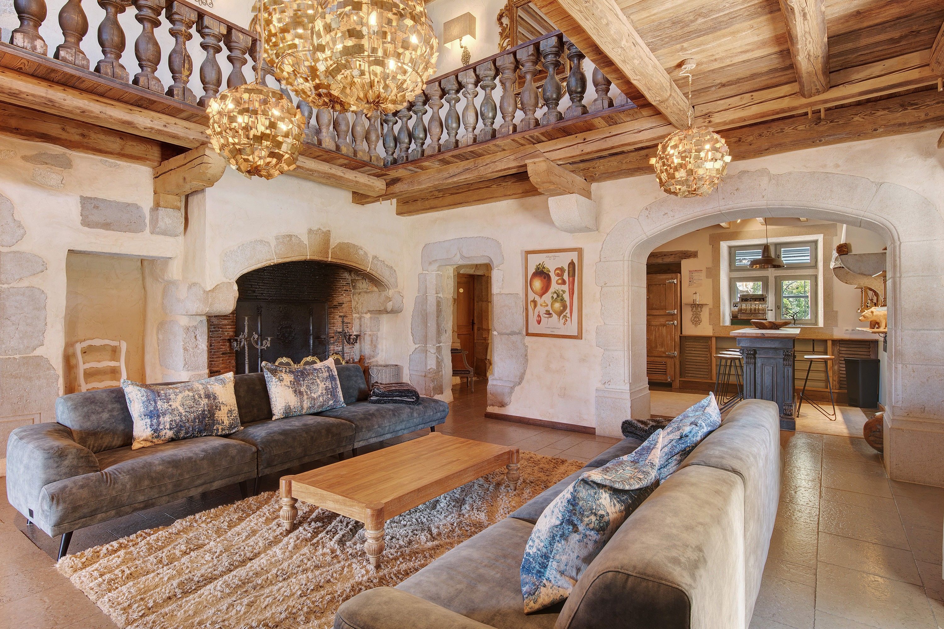 Un intérieur rustique avec une cheminée en pierre, des poutres en bois et un coin repas.