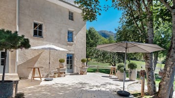 Une cour avec un patio, du mobilier d’extérieur, des plantes en pot et une vue sur une montagne.