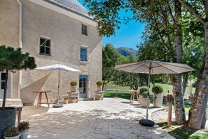 A courtyard with a patio, outdoor furniture, potted plants, and a view of a mountain. - Château 'Le Chateau Des Girards' authentically renovated (Lans-en-Vercors)