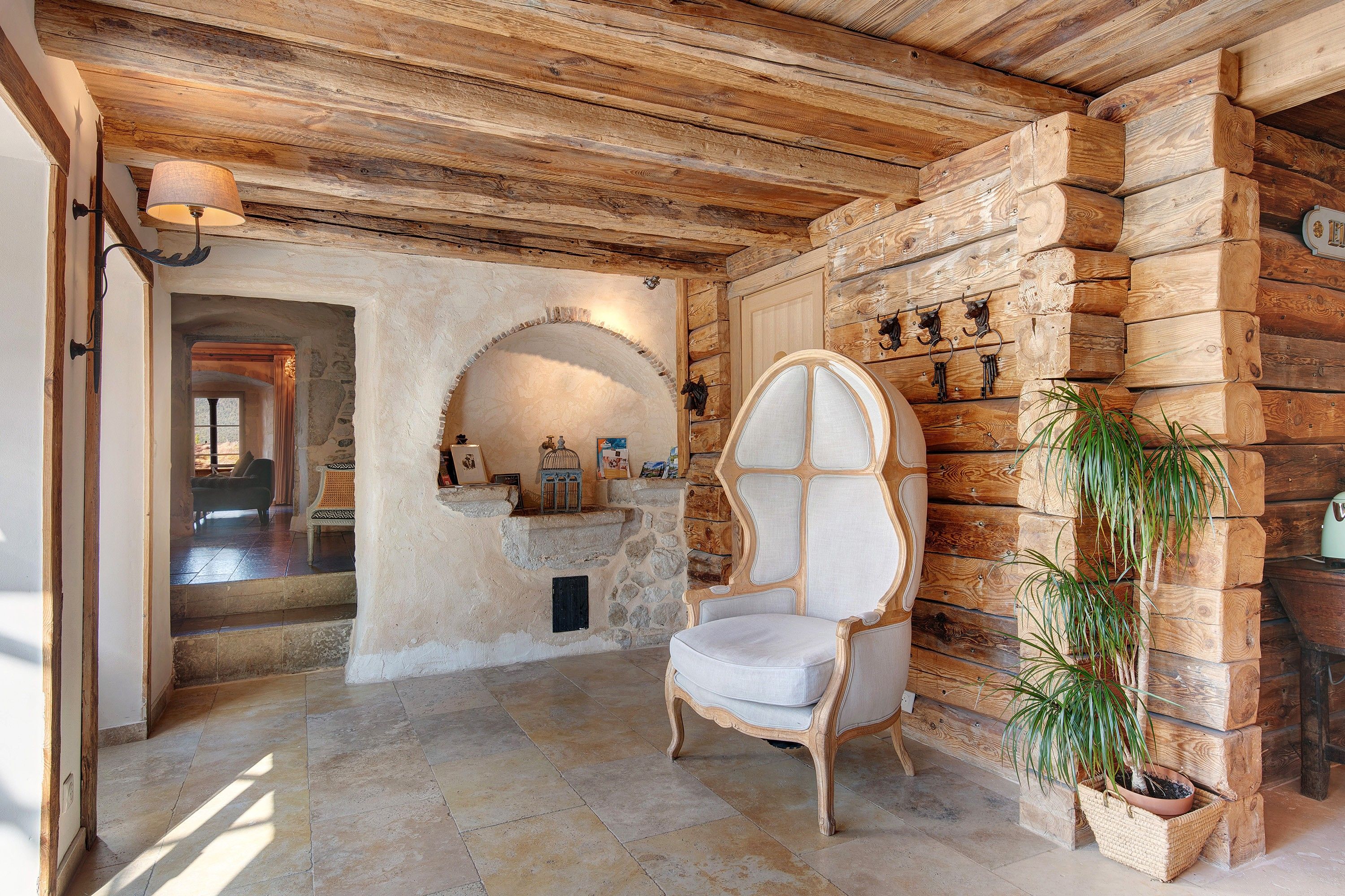 A rustic interior with a stone fireplace, a wooden wall with a chessboard, and a chair.
