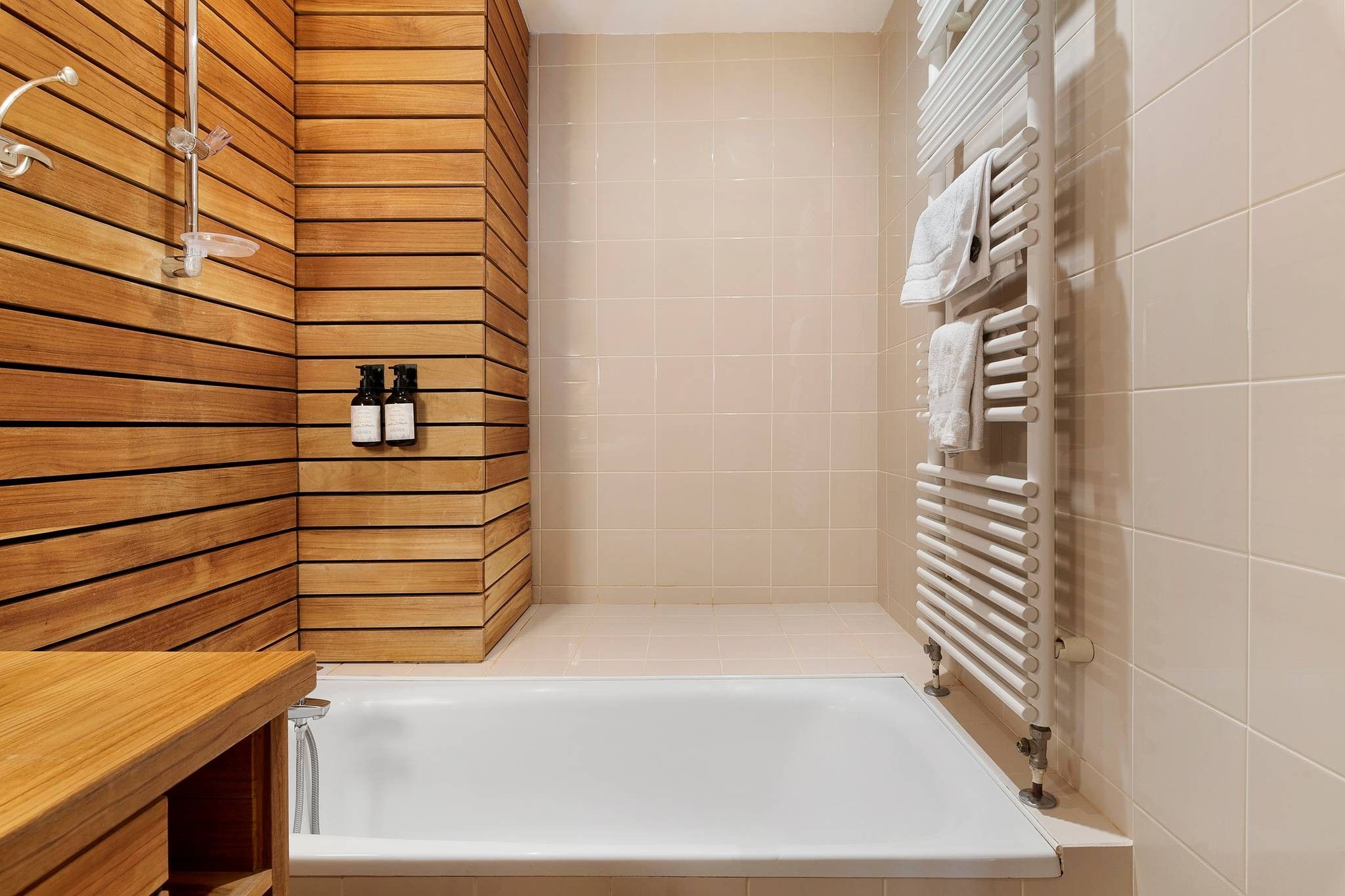 Un baño moderno con pared de madera, una bañera blanca y un perchero con toallas.