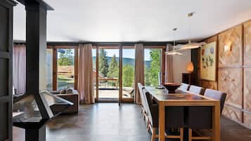 Un intérieur moderne agrémenté d’une cheminée, d’un coin repas et de grandes fenêtres offrant une vue panoramique.