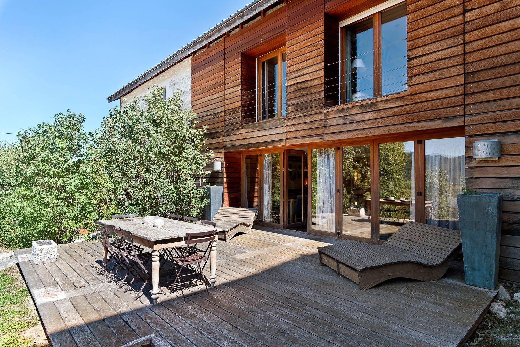 Une maison en bois avec une terrasse, une table et des chaises.