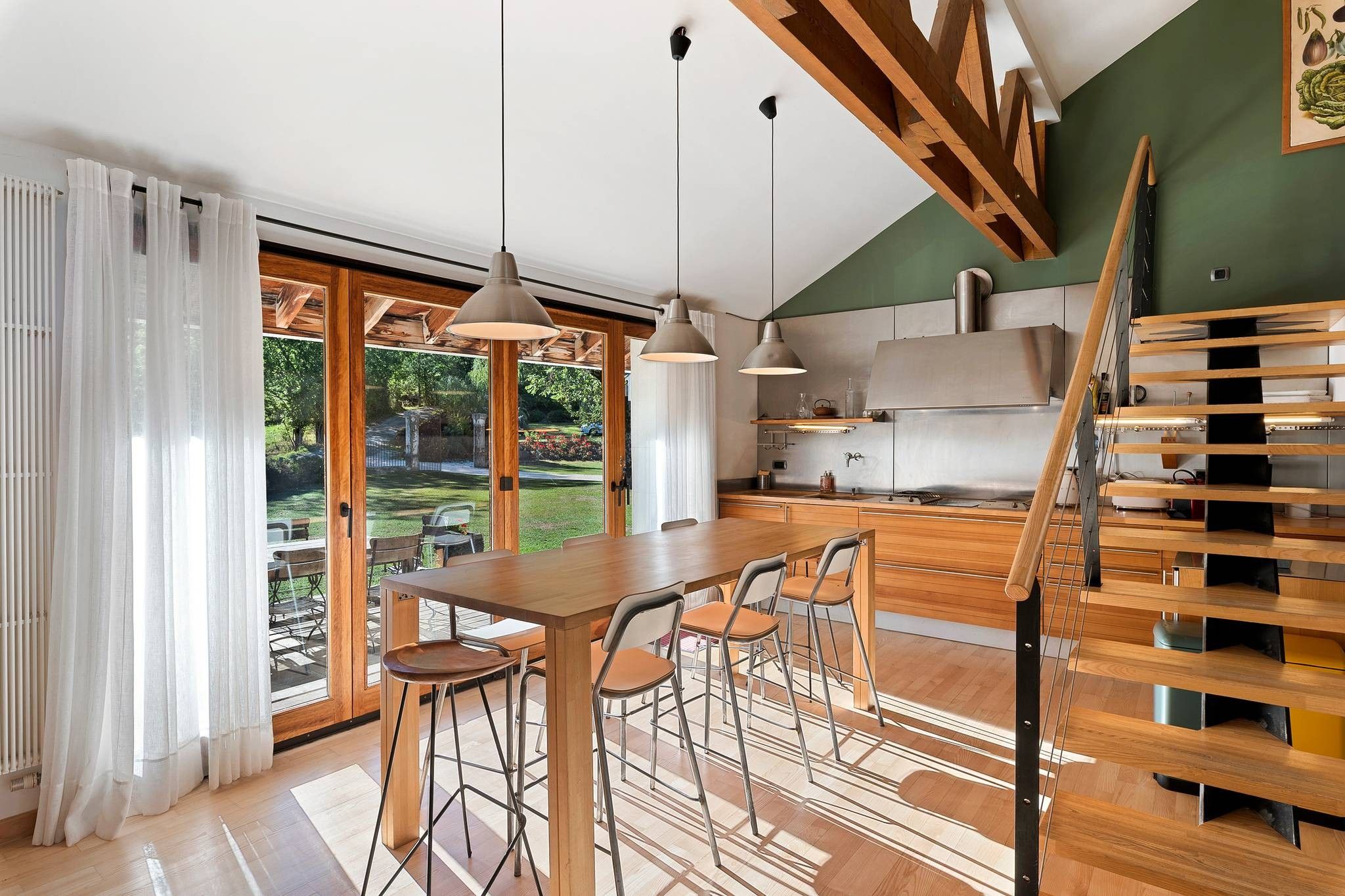 Une cuisine moderne avec un coin repas, des poutres en bois et une vue sur l’extérieur.