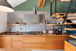 Een moderne keuken met houten kastjes, roestvrijstalen apparatuur en een hangende kruidenrek.