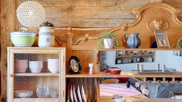 Une cuisine rustique avec des étagères en bois, un luminaire suspendu et divers ustensiles de cuisine.