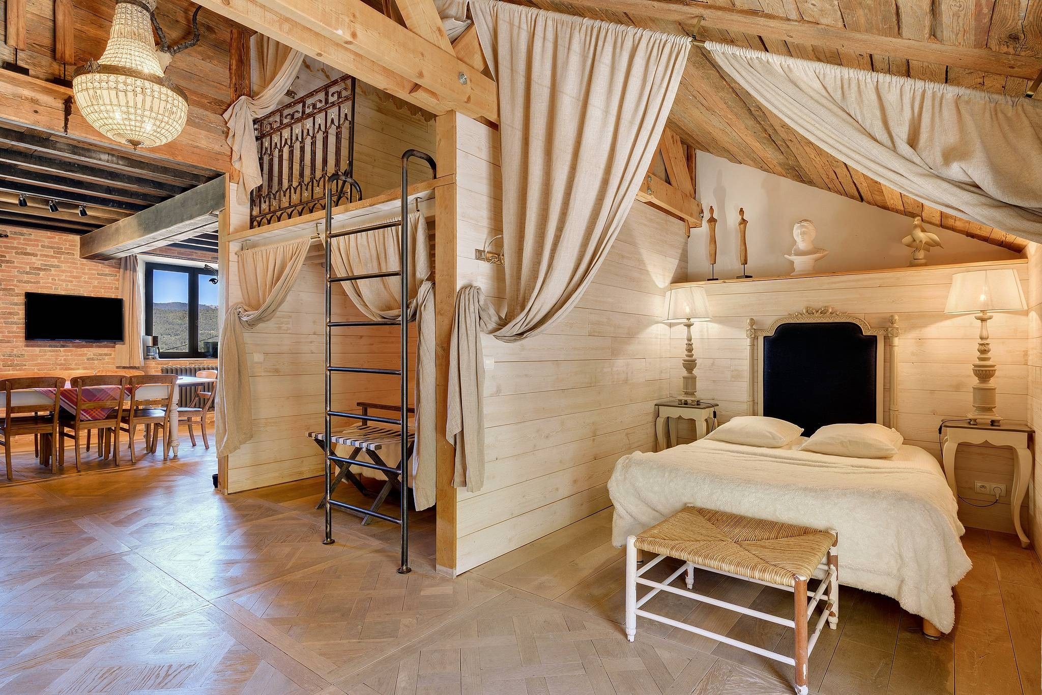 Una camera da letto rustica con un letto, una scala, una sedia di legno e un tavolo.