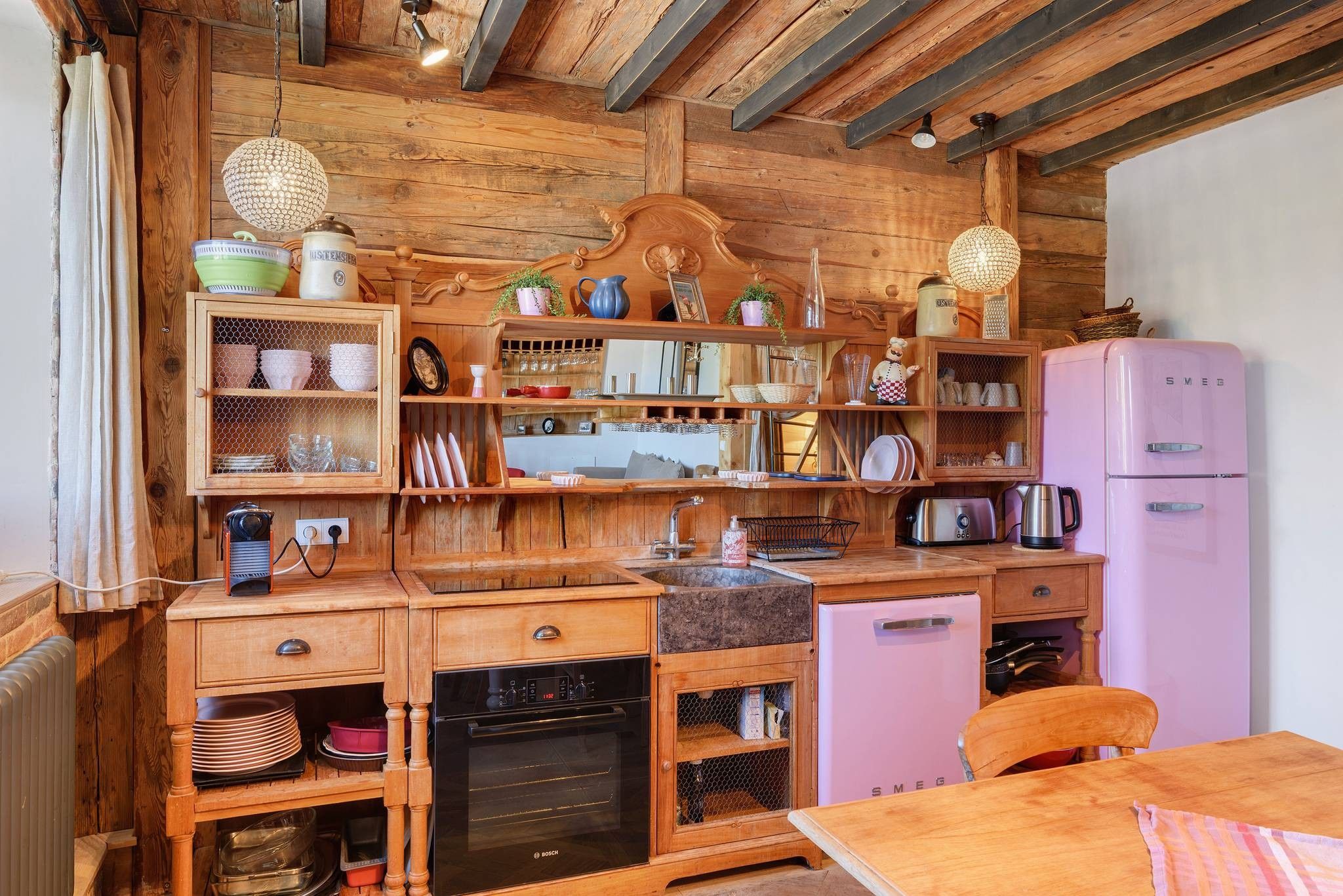 Une cuisine rustique avec des meubles en bois, un réfrigérateur rose et divers appareils de cuisine.