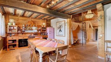 Une cuisine rustique avec des poutres en bois, une table à manger et un réfrigérateur ancien.