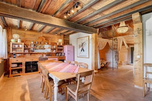 Una cocina rústica con vigas de madera, una mesa de comedor y un refrigerador antiguo.