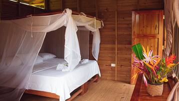 Una habitación de madera con una cama con dosel, una puerta de madera y una planta en maceta con flores.